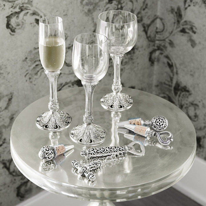 Brighton wine glasses styled with chrome bottle stoppers and an openeron a mirrored table with damask backdrop