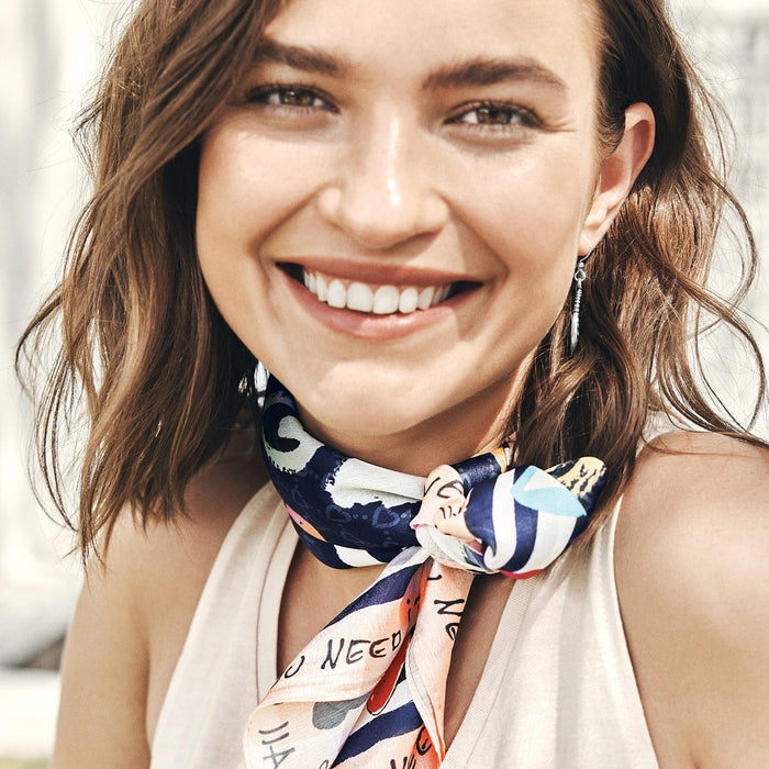 Model wearing a Brighton silk scarf with navy, peach, and white abstract graphic print, knotted at neck