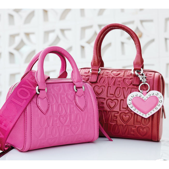 Brighton handbags in pink and red leather with embossed LOVE lettering, hearts, and heart charm on a white background