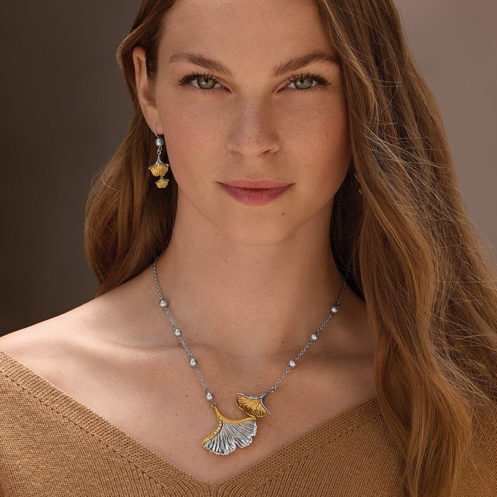 Model wearing a Brighton two-tone ginkgo leaf necklace with crystal accents paired with matching ginkgo drop earrings