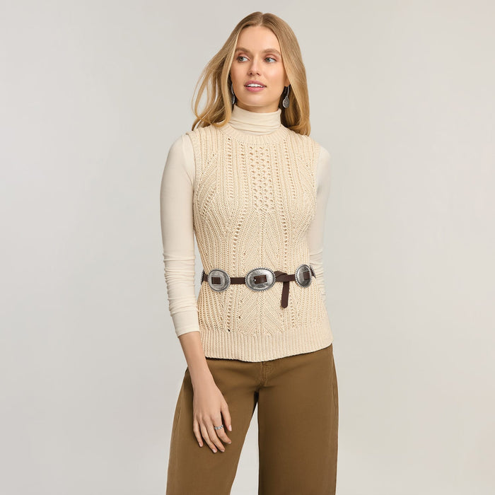 Model wearing a Brighton leather belt with three silver-tone concho medallions over a cream cable-knit top