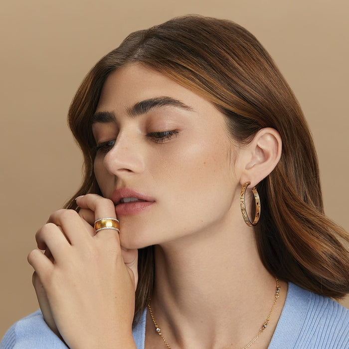 Model wearing Brighton gold-plated hoop earrings with openwork detail and coordinating Brighton crystal rings and necklace
