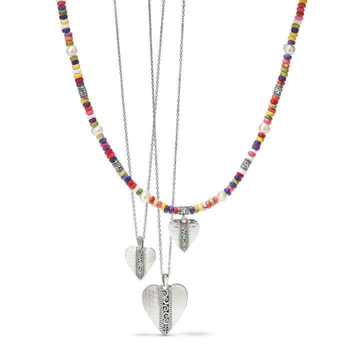 Brighton layered necklaces with silver-plated hammered heart pendants, colorful heishi beads, and potato pearls on a white background