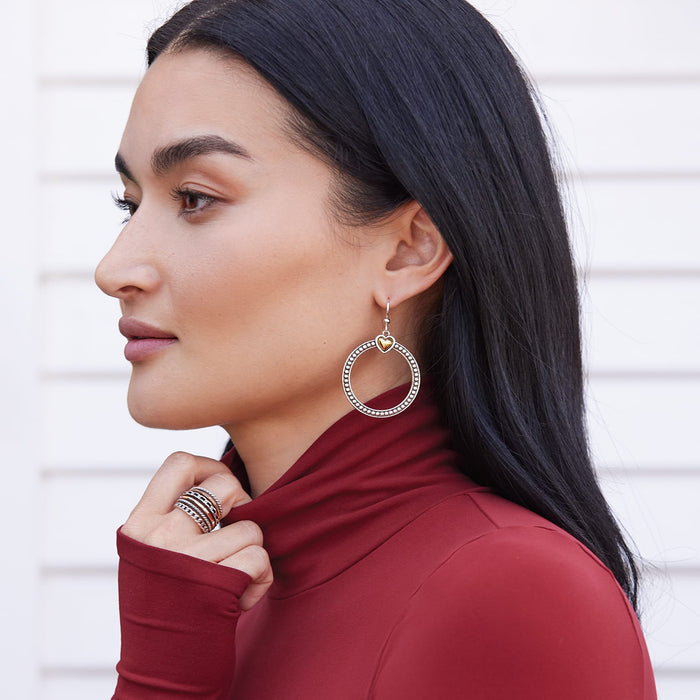 Model wearing Brighton two-tone hoop drop earrings with beaded circle frame and gold heart accent