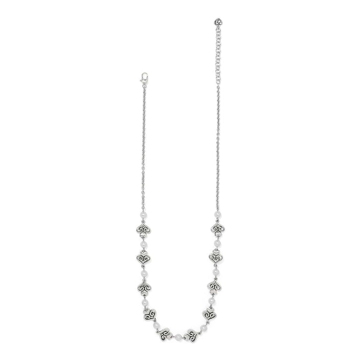 Brighton silver-plated necklace with glass pearls and ornate scroll heart stations along the chain on a white background