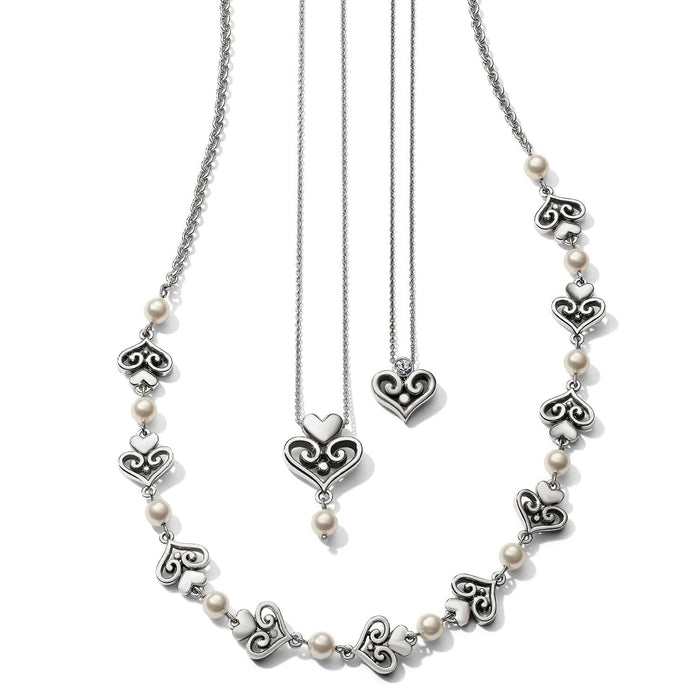 Brighton silver-plated necklaces with ornate scroll heart stations, glass pearls, and crystal-accented heart pendants on a white background
