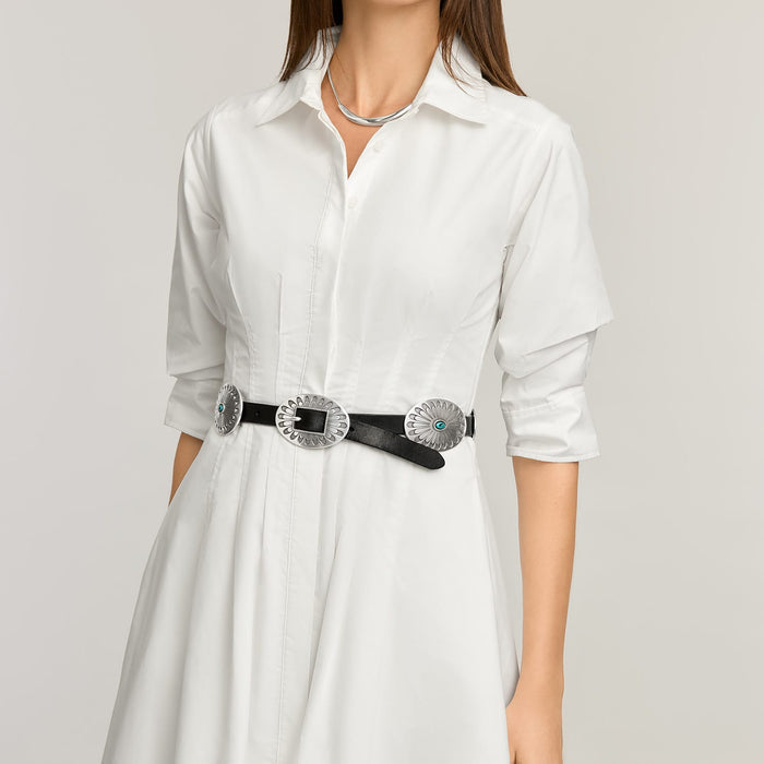 Model wearing a Brighton black leather belt with silver-tone concho medallions and turquoise accents over white shirtdress