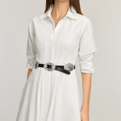 Model wearing a Brighton black leather belt with silver-tone concho medallions and turquoise accents over white shirtdress