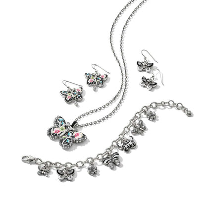 Brighton silver-plated butterfly jewelry set styled with floral enamel pendant necklace, earrings, and charm bracelet on white