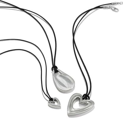 Brighton necklaces with silver-plated heart and teardrop pendants on black cords on a white background