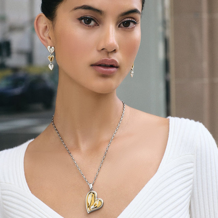 Model wearing a Brighton two-tone heart pendant necklace paired with matching tiered heart drop earrings