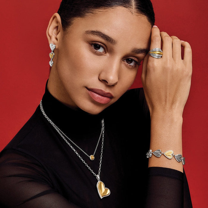 Model wearing Brighton two-tone heart drop earrings and pendant necklace with coordinating Brighton accessories