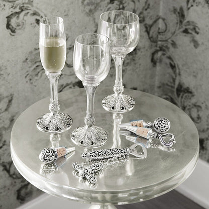Brighton wine glasses styled with chrome bottle stoppers and an openeron a mirrored table with damask backdrop