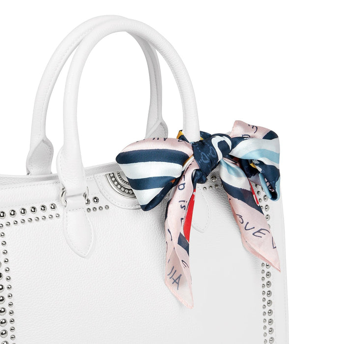 Close-up of Brighton white leather handbag with silver-tone studs and printed silk scarf tied around handle