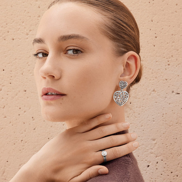 Model wearing Brighton silver heart drop earrings with scroll filigree design paired with a silver pearl ring