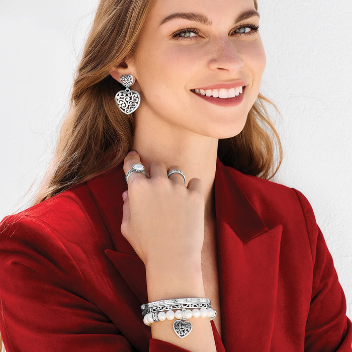 Model wearing Brighton silver heart drop earrings with scroll detail and coordinating Brighton accessories including rings and bracelets