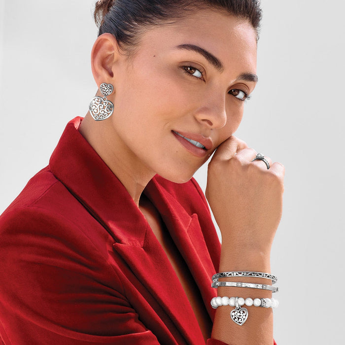Model wearing Brighton silver-plated heart drop earrings with coordinating Brighton bangles, pearl bracelet, and ring