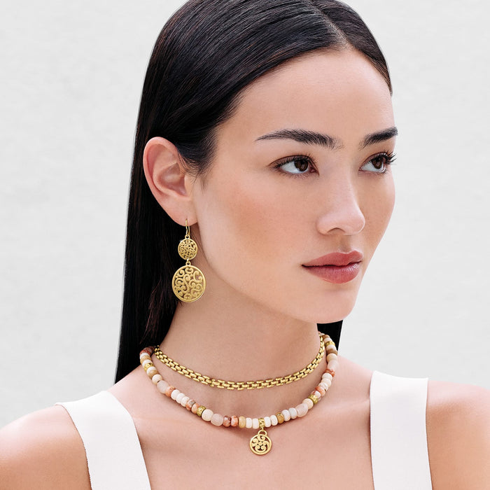Model wearing Brighton gold-plated drop earrings with ornate scroll medallions and coordinating Brighton beaded necklaces