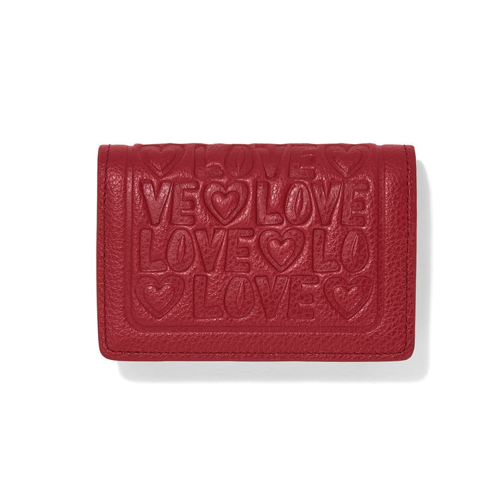 Brighton red leather wallet with embossed LOVE lettering and heart motifs across the front flap on a white background