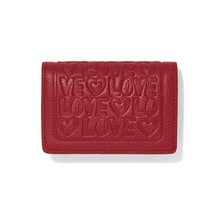 Brighton red leather wallet with embossed LOVE lettering and heart motifs across the front flap on a white background