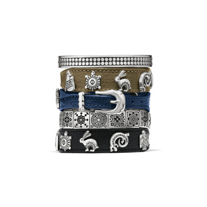 Brighton stacked bracelets in tan, blue, and black leather with silver-plated buckle, charms, and bangle on a white background