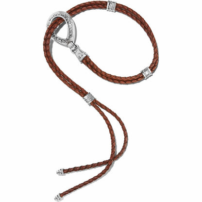 Brighton bolo necklace with braided brown leather cords and silver-tone oval loop with engraved details on a white background