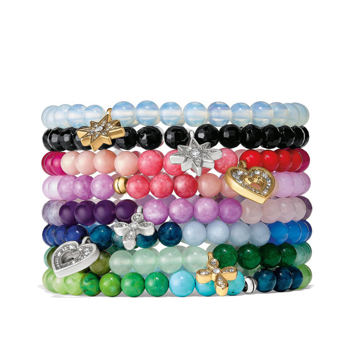 Brighton stretch bracelets stacked with multicolored beads, crystal stars, hearts, and gold and silver charms on a white background