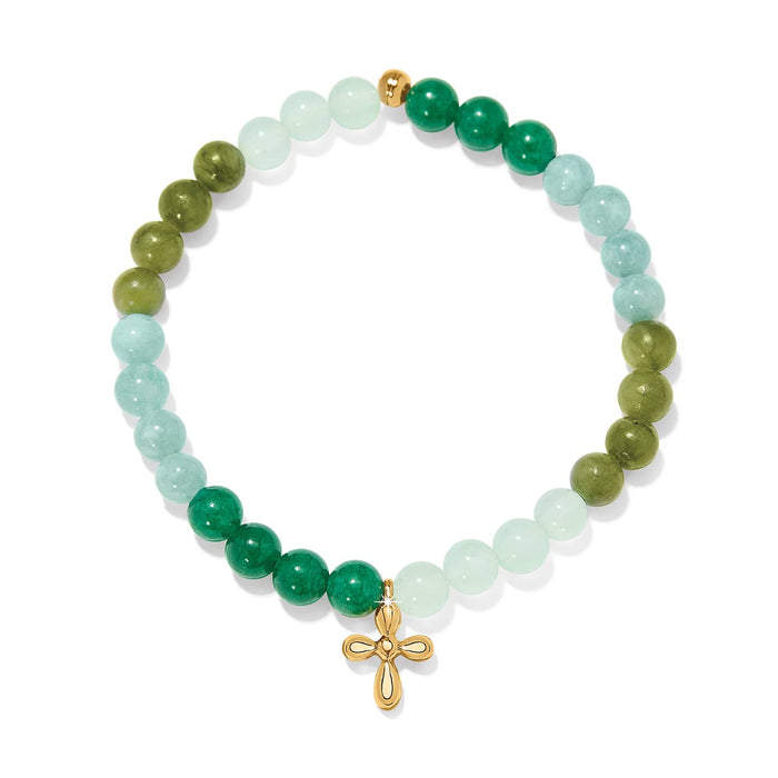 Brighton beaded bracelet with green tone beads and gold-plated cross charm on a white background