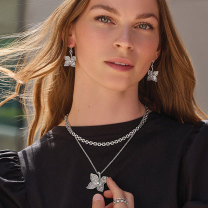 Model wearing Brighton silver-plated flower drop earrings paired with a layered chain necklace and floral crystal pendant