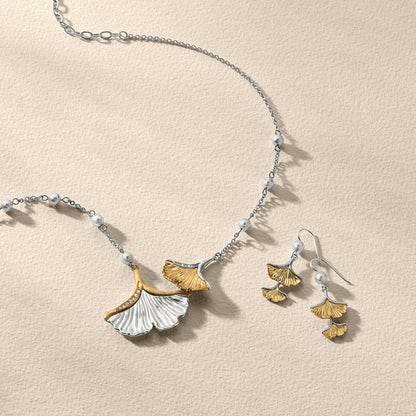 Brighton two-tone ginkgo leaf necklace and matching earrings styled with pearl bead chain accents on neutral background