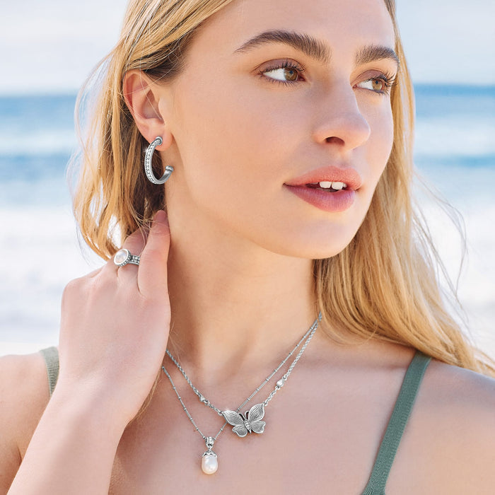 Model wearing a Brighton silver-plated butterfly necklace with rice pearl pendant and coordinating Brighton accessories