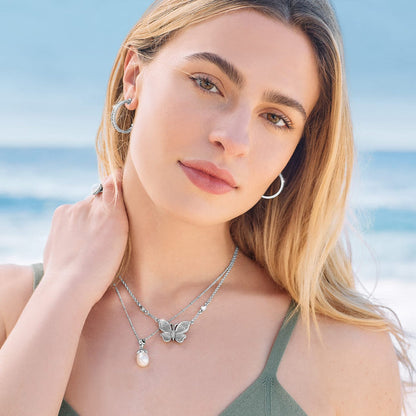 Model wearing a Brighton silver-plated butterfly necklace with rice pearl pendant and coordinating Brighton accessories