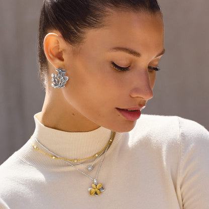 Model wearing Brighton silver-plated floral earrings with coordinating Brighton layered necklaces in silver and gold finishes