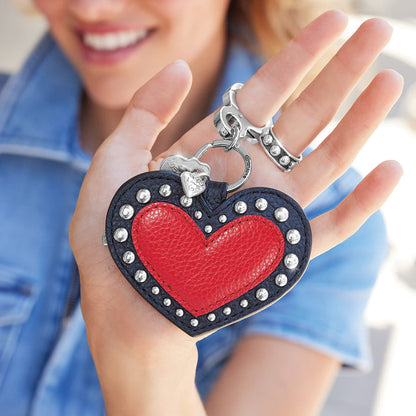 Brighton heart-shaped leather key fob in red and navy with silver-tone studs and clip in model's hand