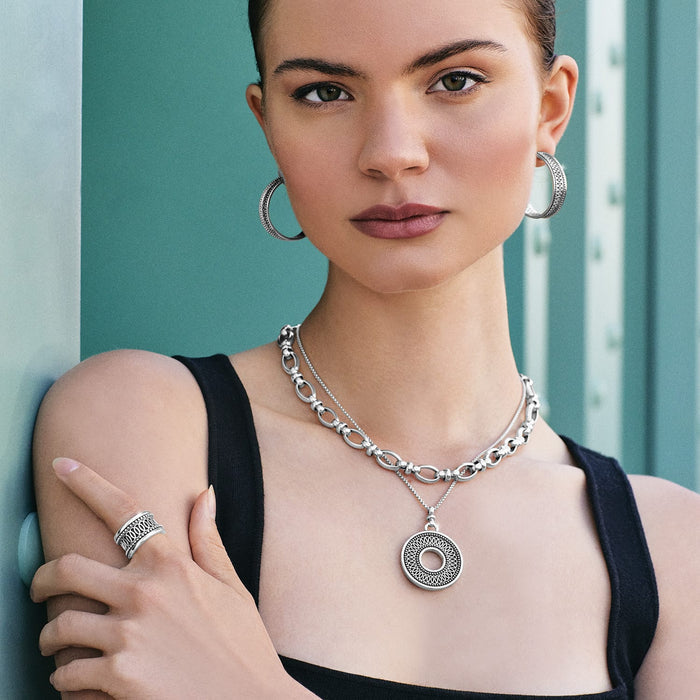 Model wearing a Brighton silver-plated medallion pendant necklace with coordinating Brighton hoop earrings and statement ring