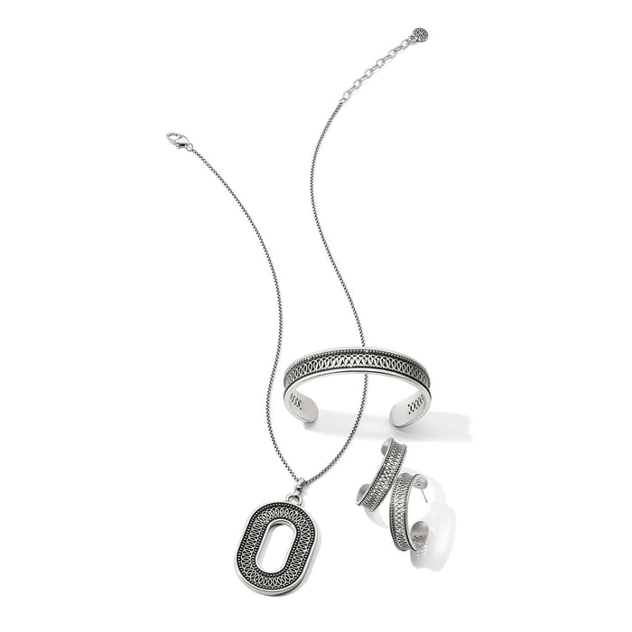 Brighton silver-plated jewelry set styled with an oval pendant necklace, cuff bracelet, and hoop earrings on white