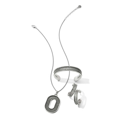 Brighton silver-plated jewelry set styled with an oval pendant necklace, cuff bracelet, and hoop earrings on white