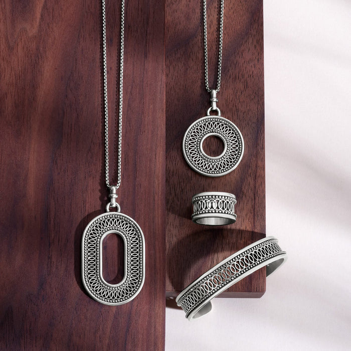 Brighton silver-plated jewelry set styled with matching pendant necklaces, ring, and cuff bracelet on wooden surface