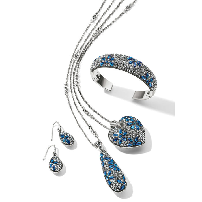 Brighton jewelry set styled with silver-tone necklaces, teardrop earrings, heart pendant, and crystal-encrusted cuff bracelet with blue accents