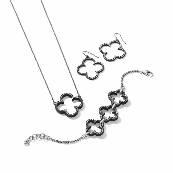 Brighton jewelry set with black lacquer clover motifs, crystal accents, and silver-plated chains on a white background