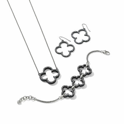 Brighton jewelry set with black lacquer clover motifs, crystal accents, and silver-plated chains on a white background
