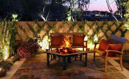 Outdoor patio with fire pit, chairs, and decorative elements at dusk.