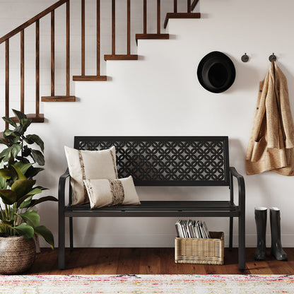 Durable garden bench with a black steel frame and floral lattice design, placed near a staircase and potted plant.