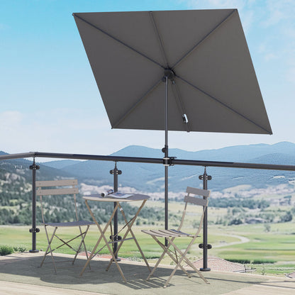 Gray rectangular patio umbrella with a metal frame, positioned over a small table and chairs on a balcony.
