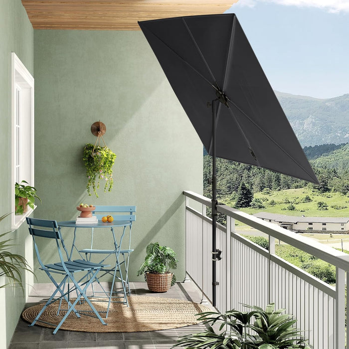 Rectangular flat patio market umbrella in dark gray, positioned on a balcony with blue chairs and a table.