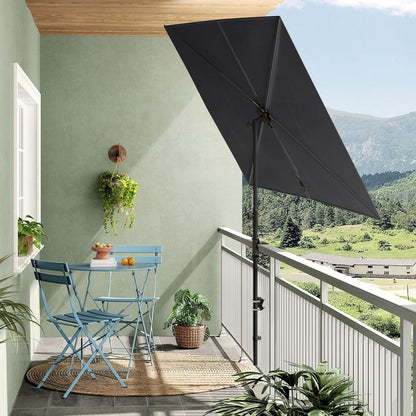 Rectangular flat patio market umbrella in dark gray, positioned on a balcony with blue chairs and a table.