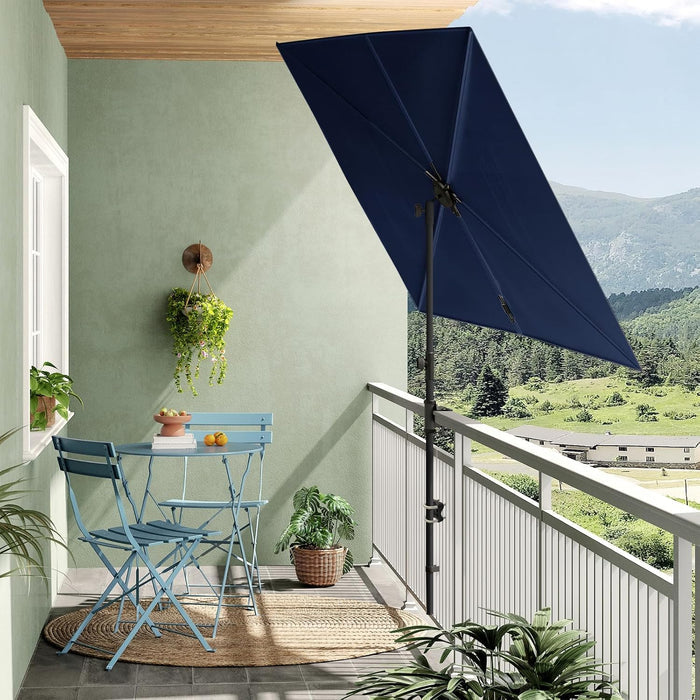 Rectangular flat patio market umbrella in navy blue, positioned over a small balcony table and chairs with a scenic view.