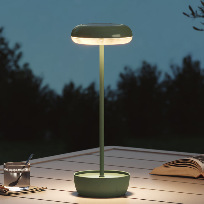 Green outdoor lamp on a wooden surface with a dark background