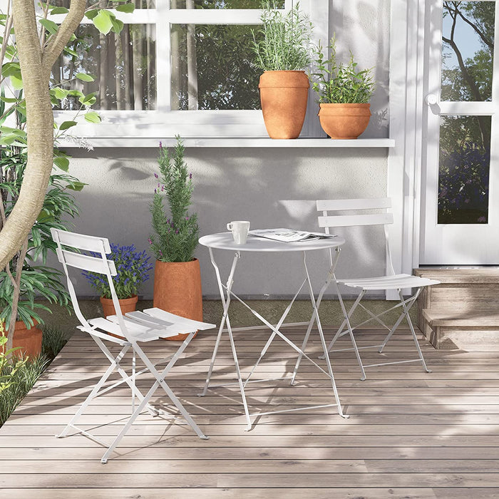 White outdoor furniture set on a wooden deck with plants and a window in the background.