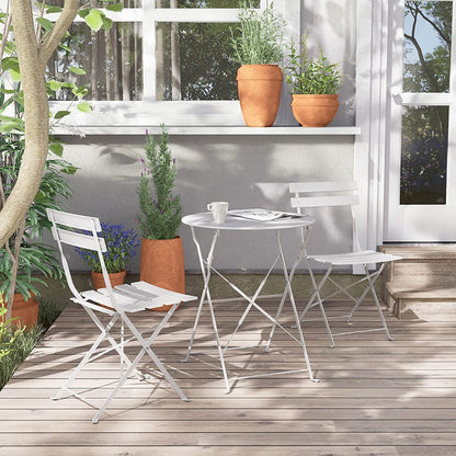 White outdoor furniture set on a wooden deck with plants and a window in the background.